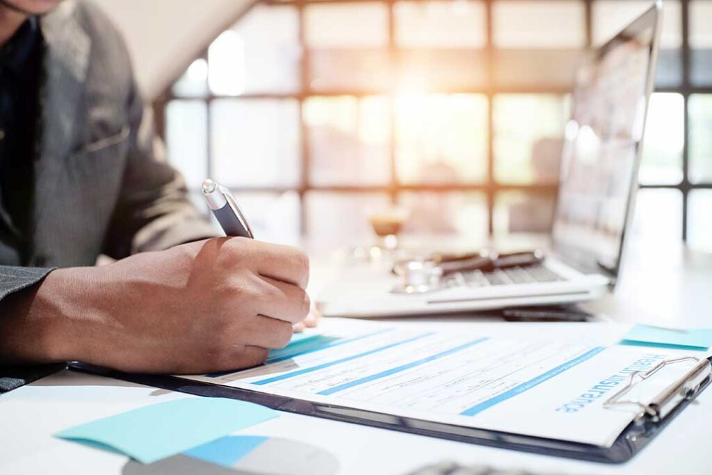 A homeowner reviews an insurance renewal notice beside a calculator and policy documents.