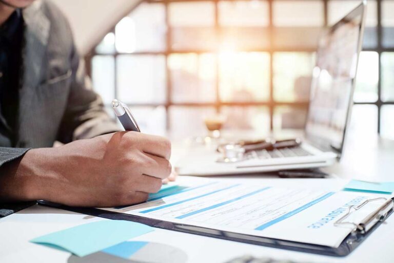 A homeowner reviews an insurance renewal notice beside a calculator and policy documents.