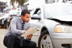 Insurance adjuster reviewing accident photos and claim documents with a policyholder at a table.